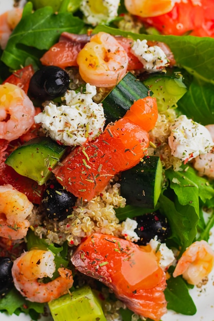 insalata con quinoa, lattuga iceberg, rucola, cetriolo, olive nere, pomodoro, ricotta, salmone, gamberi e salsa di mango