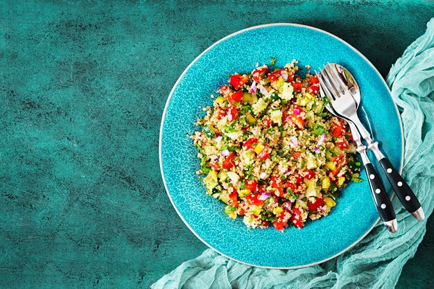 Insalata con quinoa, rucola, peperoni, pomodori e cetriolo in ciotola