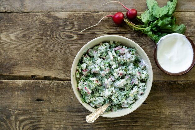 Insalata con ravanello, aneto e panna acida su un fondo rustico