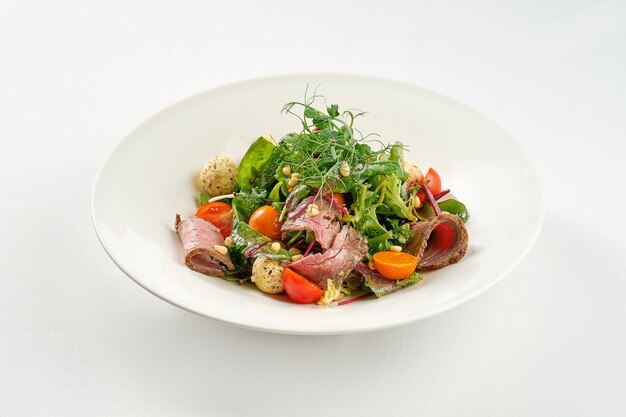 Insalata con roast beef e pinoli in un piatto bianco.