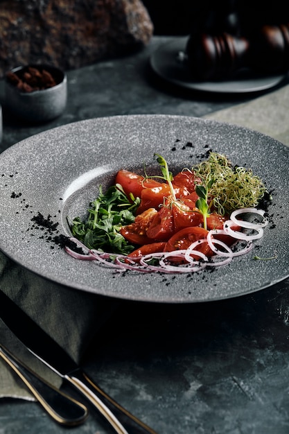 Insalata con rucola e pomodori e cipolle marinati freschi.