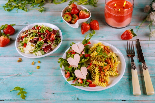 Insalata con rucola, rotini con hot dog e fragole