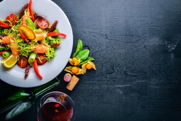 Insalata con salmone e verdure fresche ed erbe aromatiche Cucina italiana Vista dall'alto su fondo in legno