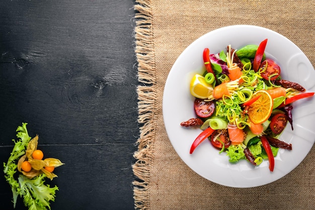 Insalata con salmone e verdure fresche ed erbe aromatiche. Cucina italiana. Vista dall'alto. Su Fondo In Legno.