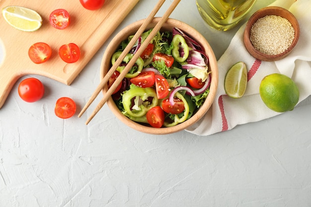 Insalata con sesamo e accessori per la cucina su grigio