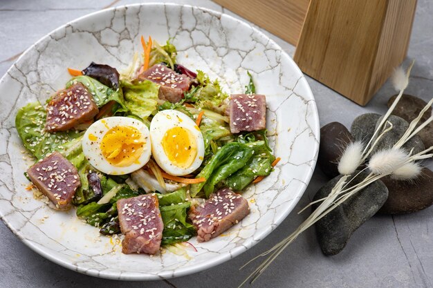 insalata con uovo di erbe aromatiche di lattuga di tonno su un tavolo grigio