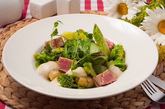 Insalata con verdure e tonno fritto su un piatto bianco. avvicinamento