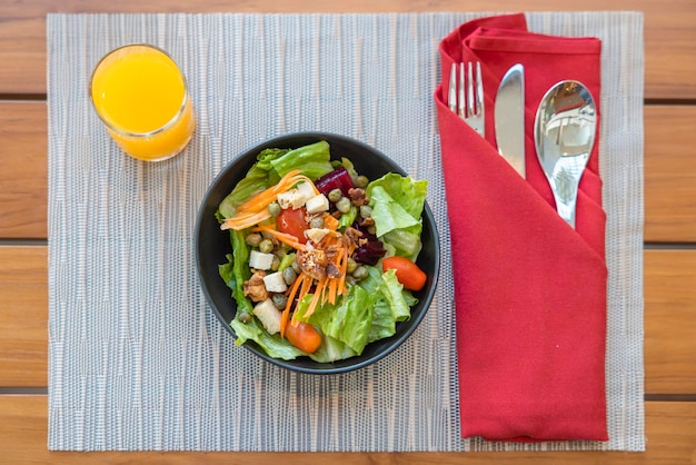 Insalata da colazione con verdure saltate e succo d'arancia e con un cucchiaio che fissa i resti dei coltelli