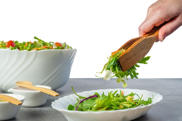 Insalata da servire a mano su un piatto con una pinza di legno accanto alla ciotola e piccoli contenitori