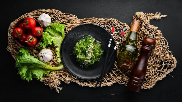 Insalata di alghe in un piatto nero Chuka wakame Sullo sfondo vecchio Vista dall'alto Spazio libero per il testo