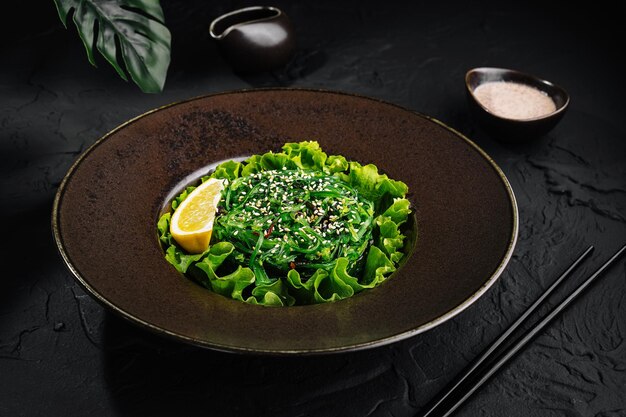 Insalata di alghe verdi fresche con semi di sesamo su un piatto scuro