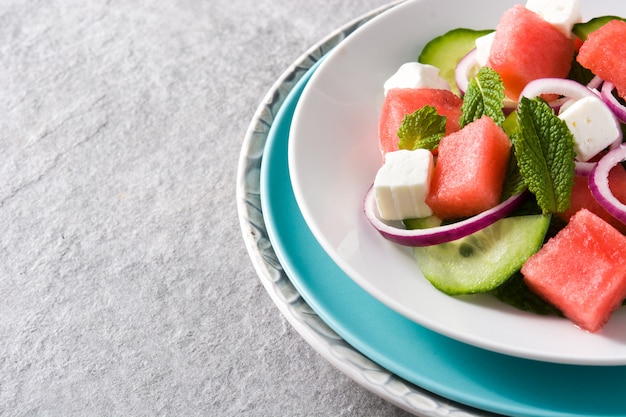 insalata di anguria con formaggio feta, menta, cipolla e cetriolo su grigio