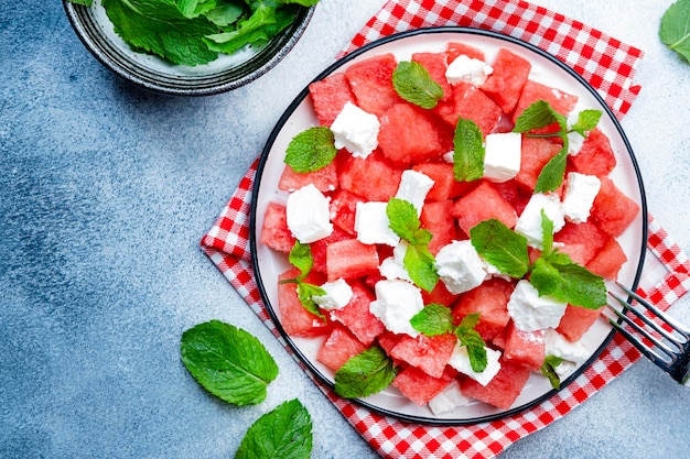 Insalata di anguria succosa estiva rinfrescante con formaggio feta e sfondo grigio menta fresca vista dall'alto spazio copia