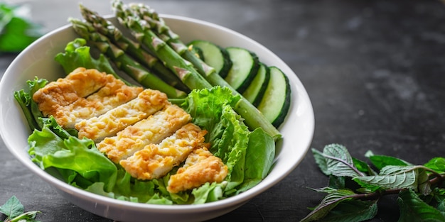 Insalata di asparagi verdi Carne di pollo Ciotola di foglie di insalata che mangiano dieta organica sul tavolo