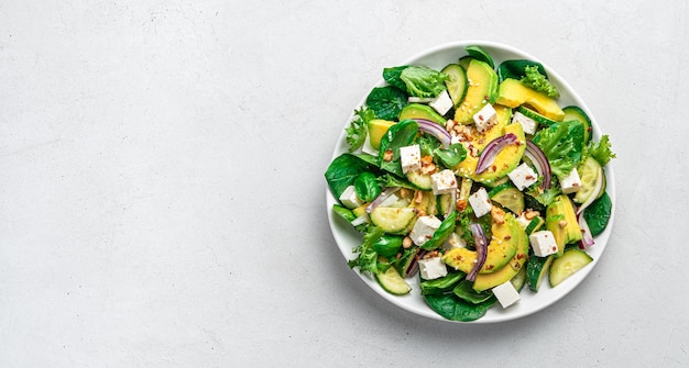 Insalata di avocado con erbe fresche cetriolo feta e semi su sfondo grigio chiaro Cibo vegetariano sano