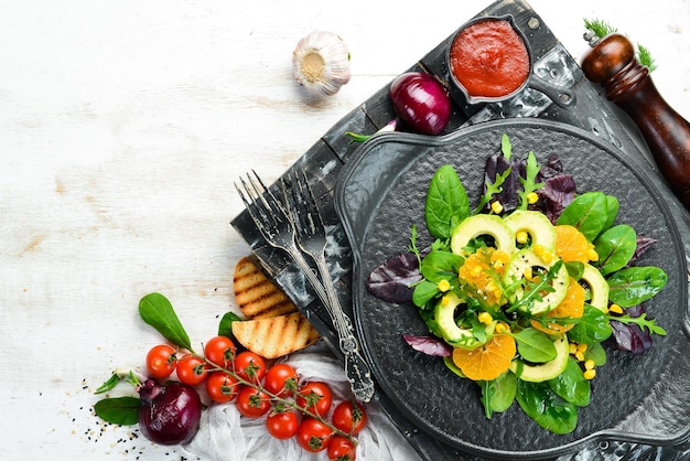 Insalata di avocado vegana fresca con arance e spinaci su un piatto nero Stile rustico Vista dall'alto Spazio libero per il testo