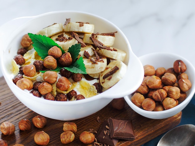 Insalata di banana con cioccolato e nocciole nello yogurt in un piatto bianco Vista dall'alto