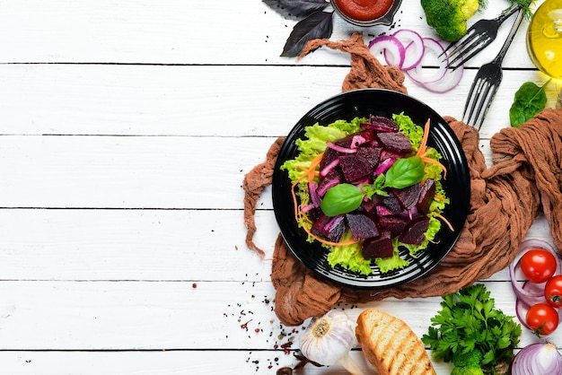 Insalata di barbabietole con cipolle in un piatto nero su sfondo bianco di legno Vista dall'alto Spazio libero per il testo