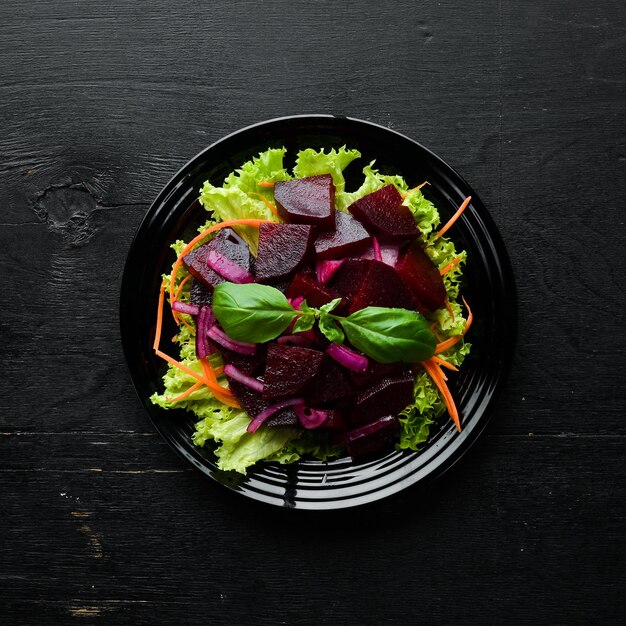 Insalata di barbabietole con cipolle in un piatto nero su sfondo nero Vista dall'alto Spazio libero per il testo