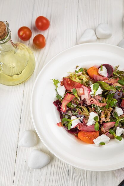 Insalata di barbabietole formaggio pomodori e verdure su un piatto bianco e un tavolo bianco