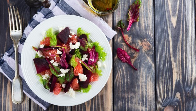 Insalata di barbabietole, lattuga, foglie di barbabietola, pompelmo e feta sullo sfondo di legno vecchio. Messa a fuoco selettiva.