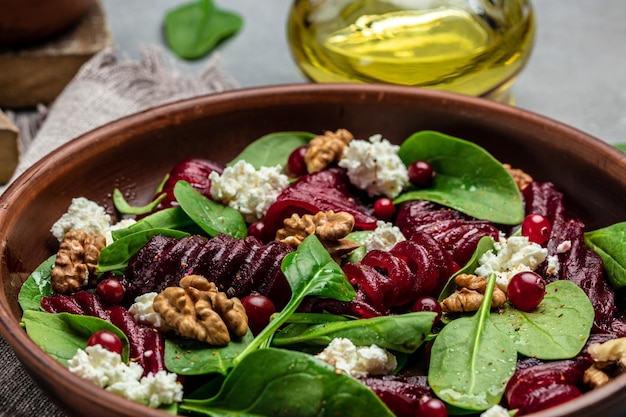 Insalata di barbabietole o barbabietole con mirtilli rossi noci formaggio spinaci su piatto con condimento a forchetta e spezie su sfondo scuro Sfondo ricetta alimentare Primo piano