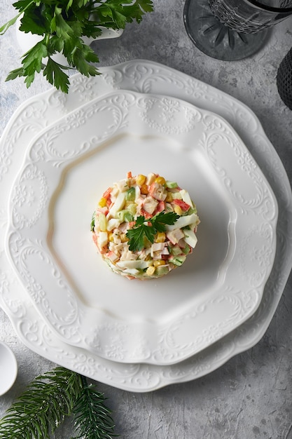 insalata di bastoncini di granchio servita nel piatto bianco sul tavolo di pietra grigia