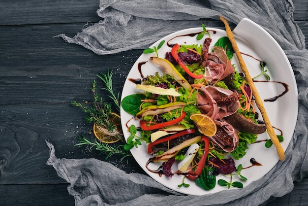 Insalata di carne e foglie di insalata. Su una superficie di legno. Vista dall'alto. Spazio libero per il tuo testo.