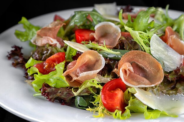 Insalata di carne secca prosciutto erbe aromatiche e pomodori su un piatto