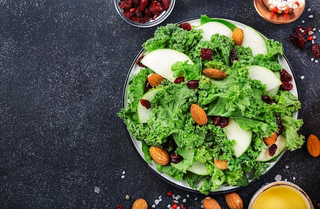 Insalata di cavolo con mele verdi e mirtilli rossi secchi e mandorle Cibo vegano sano vista dall'alto sfondo nero del tavolo da cucina