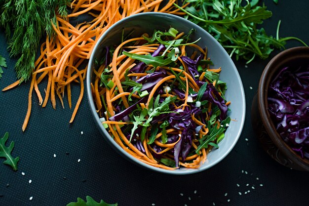 Insalata di cavolo rosso, carote e verdure. Decorato con verdure ed erbe affettate. Strisce di taglio