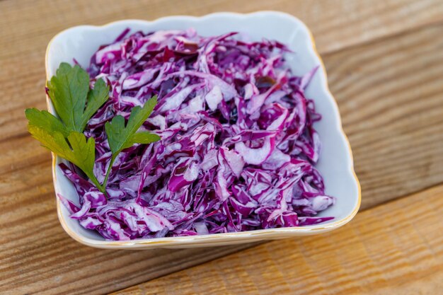 Insalata di cavolo rosso con cipolla e maionese su tavola di legno