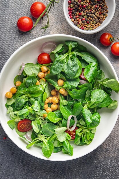 insalata di ceci, legumi, lattuga, mache, pomodoro fresco pasto sano spuntino dieta sul tavolo