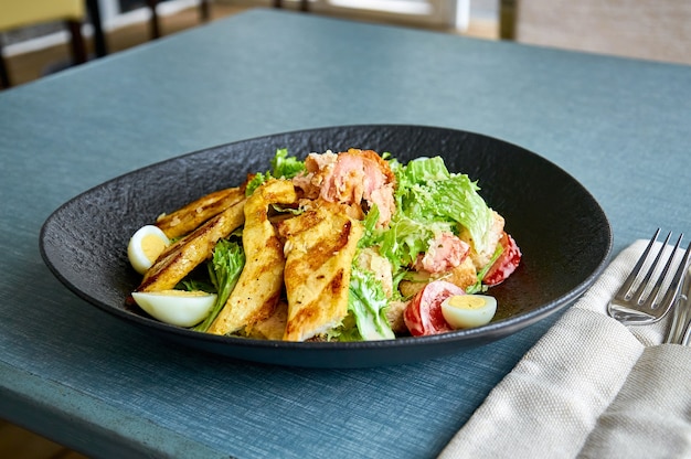 Insalata di Cesare fresca con pollo in una ciotola nera sulla veranda del ristorante