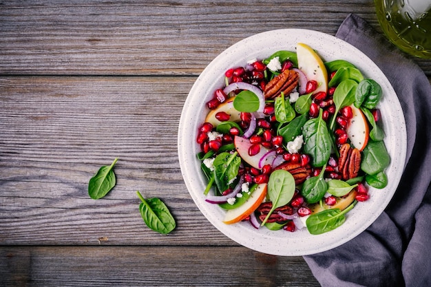 Insalata di cipolle rosse di mele pecan fatte in casa con formaggio di capra e melograno su fondo di legno