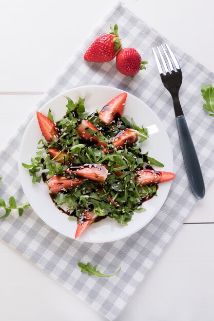 Insalata di dieta biologica sana con rucola, fragole e sesamo con glassa balsamica