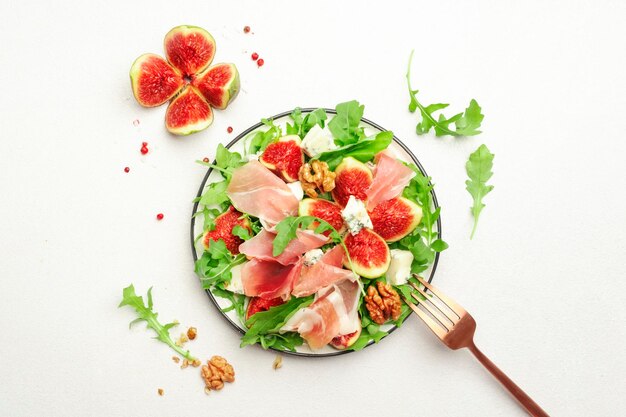 Insalata di fichi freschi con prosciutto gorgonzola noci rucola su sfondo bianco tavolo da cucina vista dall'alto spazio copia