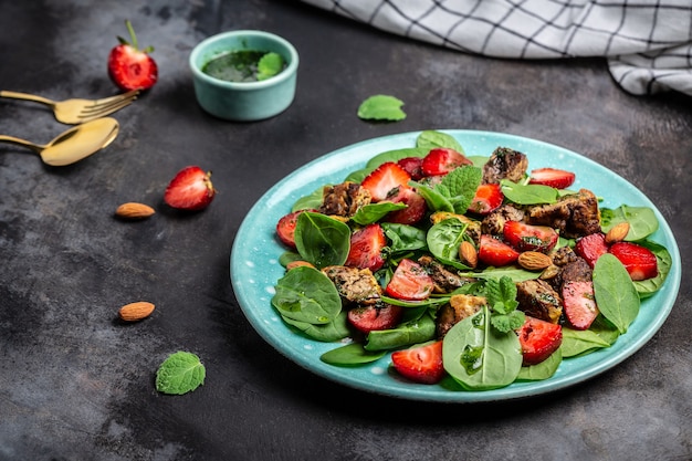 Insalata di fragole fresche con foglie di spinaci, fegatini di pollo, mandorle e menta