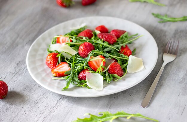 Insalata di fragole, rucola e formaggio su uno sfondo grigio. Cibo dietetico