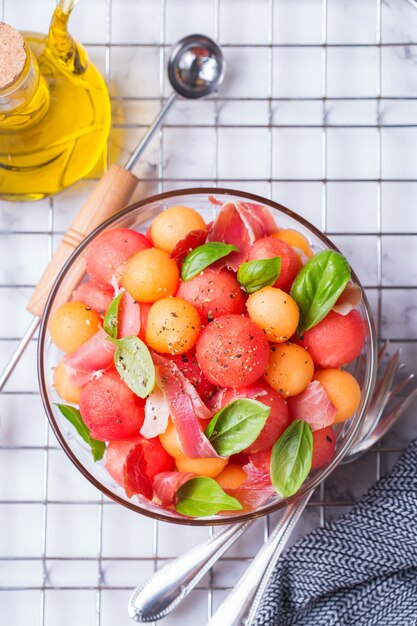 Insalata di frutta con melone melone, anguria e prosciutto in una ciotola sul tavolo della cucina