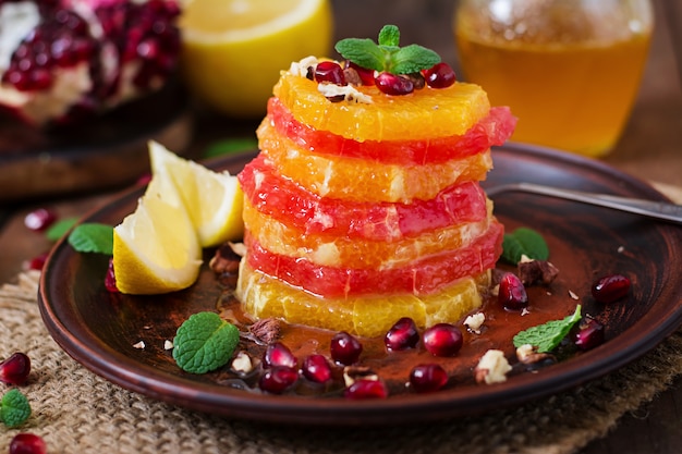 Insalata di frutta con pompelmo e arancia, semi di melograno, miele e limone, decorata con menta