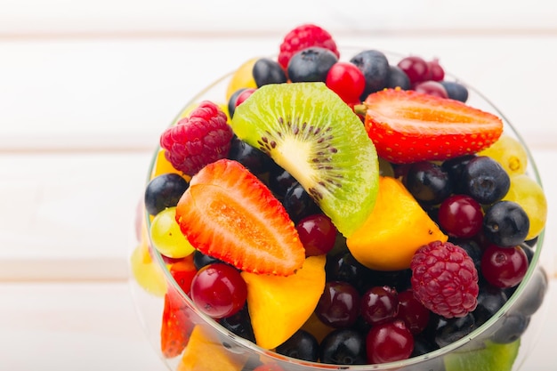 Insalata di frutta cruda in ciotola sulla tavola di legno