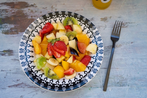 Insalata di frutta naturale e sana con arancia impostata in un piatto vintage, su una superficie rustica.