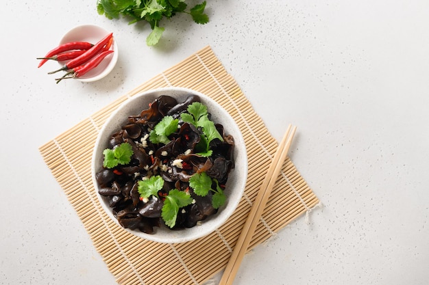 Insalata di funghi muer neri sottaceto cinese con peperoncino e foglie di coriandolo in una ciotola