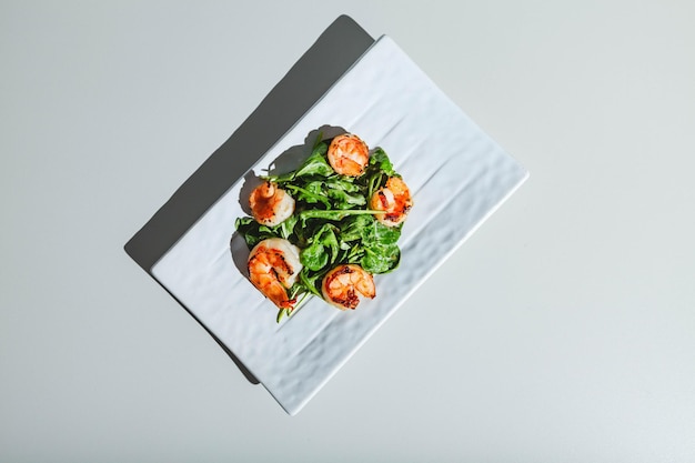 Insalata di gamberi e rucola su piatto bianco su sfondo bianco