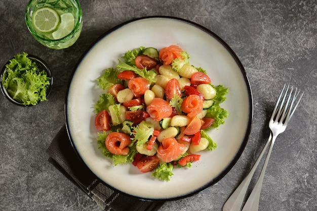 Insalata di gnocchi di patate con pomodori, cetrioli, peperoni, salmone e lattuga