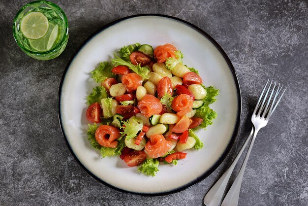 Insalata di gnocchi di patate con pomodori, cetrioli, peperoni, salmone e lattuga