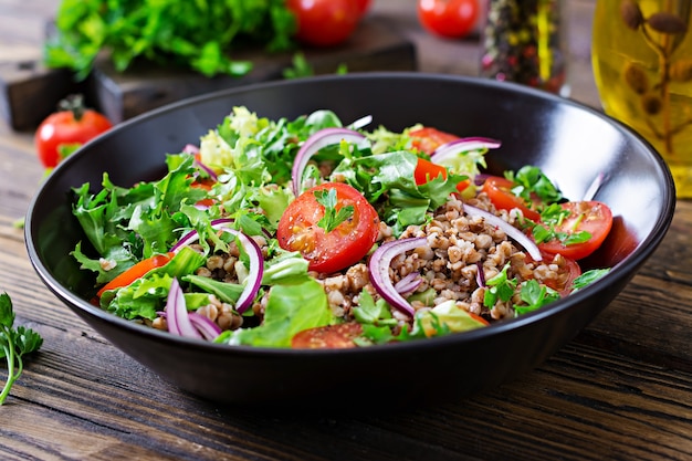 Insalata di grano saraceno con pomodorini, cipolla rossa ed erbe fresche. Cibo vegano. Menu dietetico.