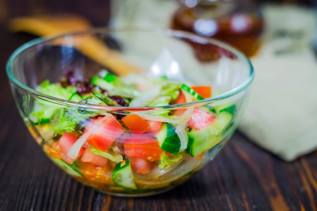 Insalata di insalata con verdure fresche in una ciotola di vetro sul tavolo