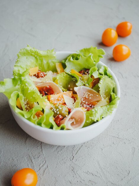 Insalata di lattuga, pomodori, olive, pomodori secchi, prosciutto di Parma, cheddar